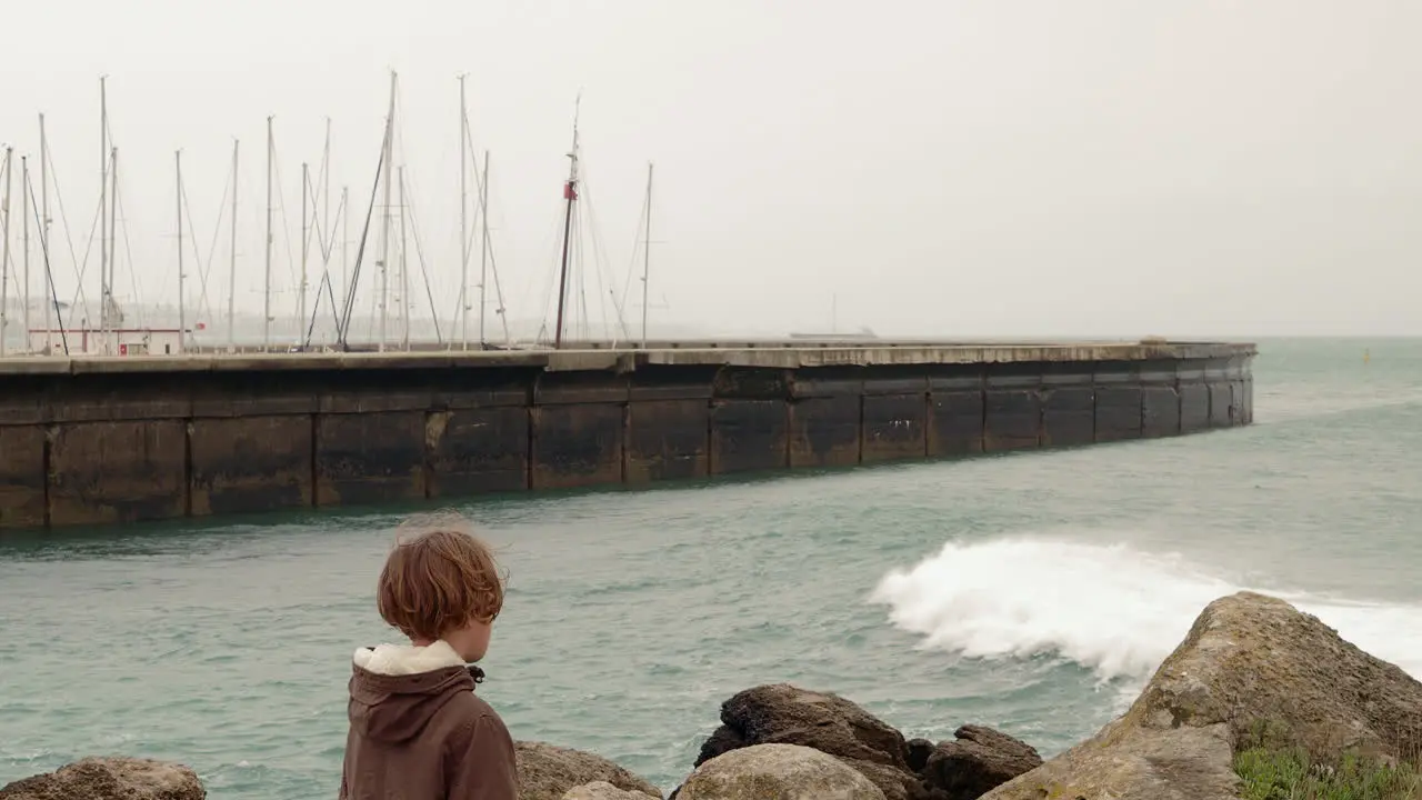 Child throwing a rock into the wavy ocean