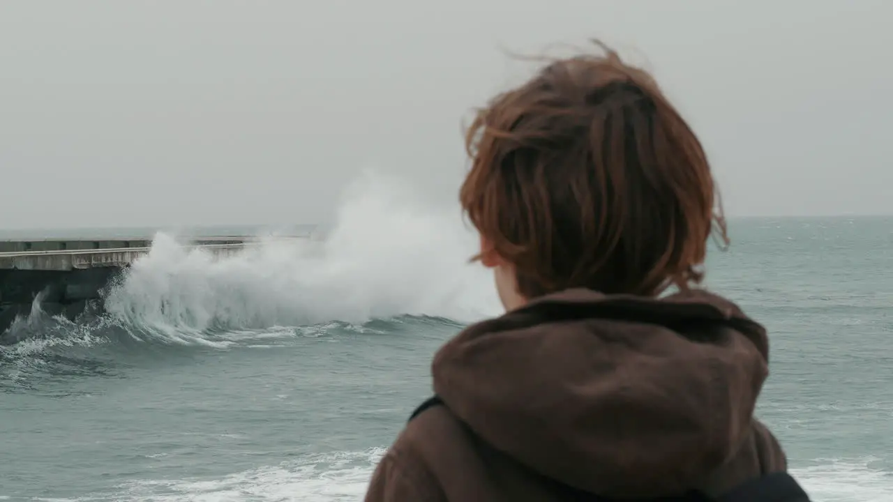 Lonely boy watching broken ocean waves