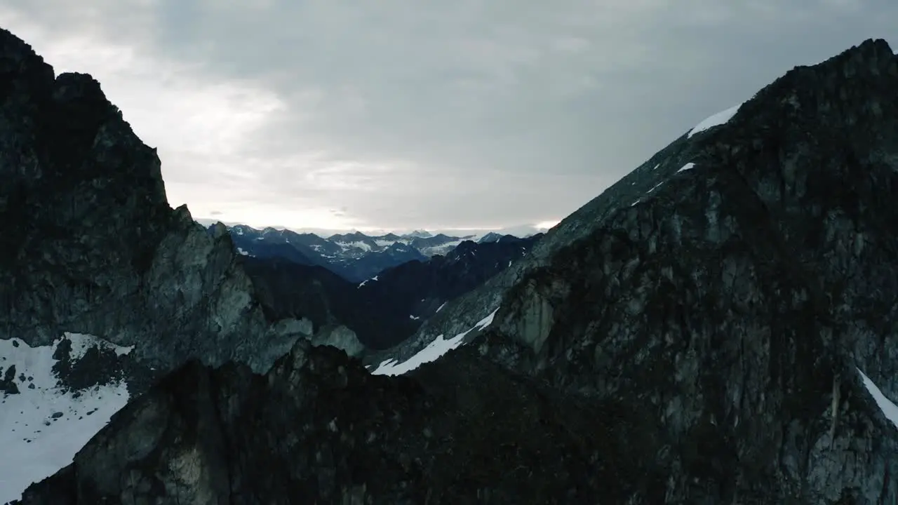 Alaskan Rugged Mountain Range Drone Flying through the Clouds and over a ridge in the Mountains at Sunrise