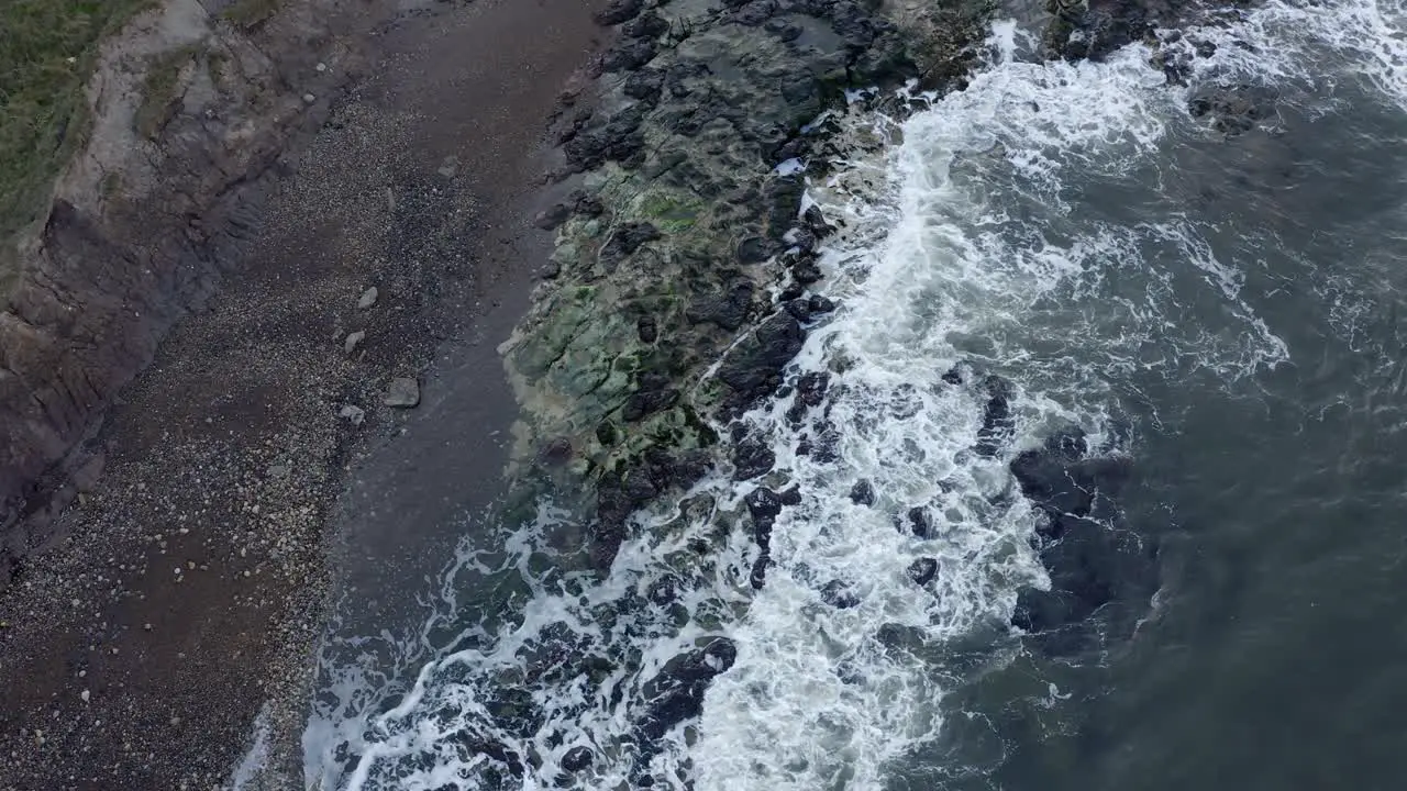 Aerial top down view of waves crashing against rocks Scarborough coastline UK