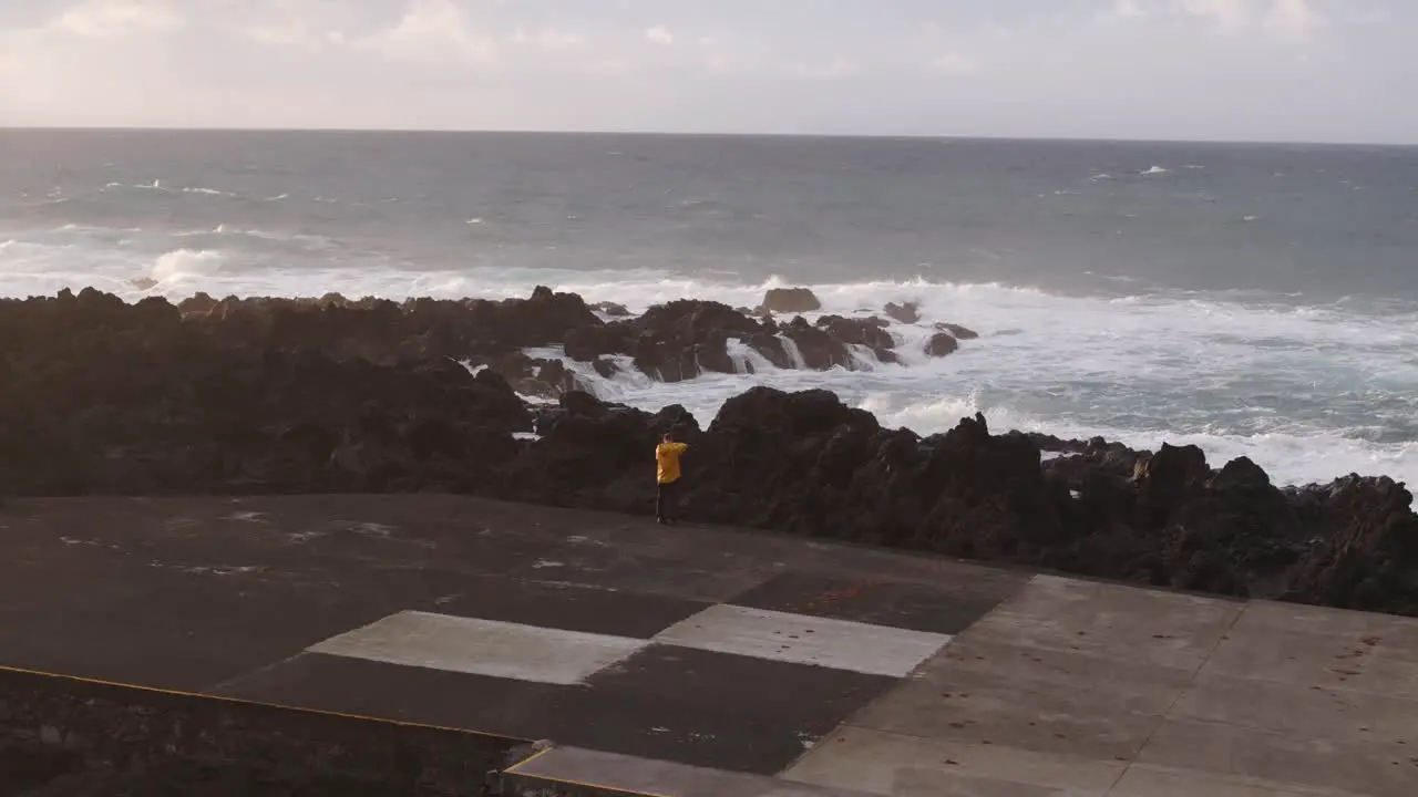 Man yellow jacket standing in front of rough sea big waves Azores Portugal