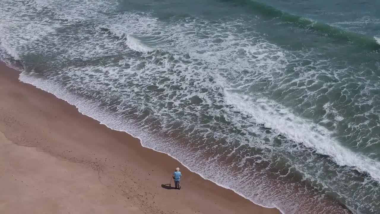 Drone Pan Over Male Fisherman Adjusting Fishing Rod on Rough Cape Cod Shoreline