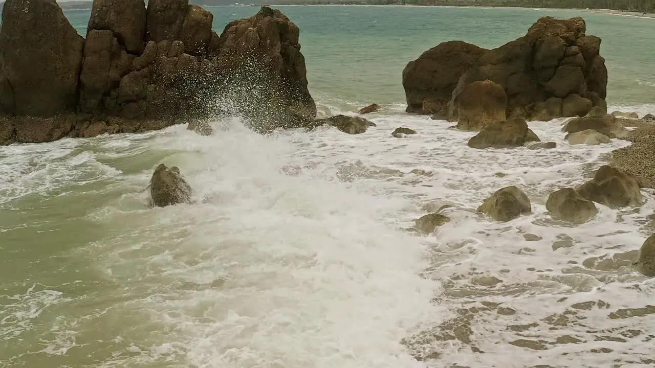 Slow motion shot of waves crashing into the rocky coastline of Banbanon Beach Surigao Del Norte Philippines on a cloudy day