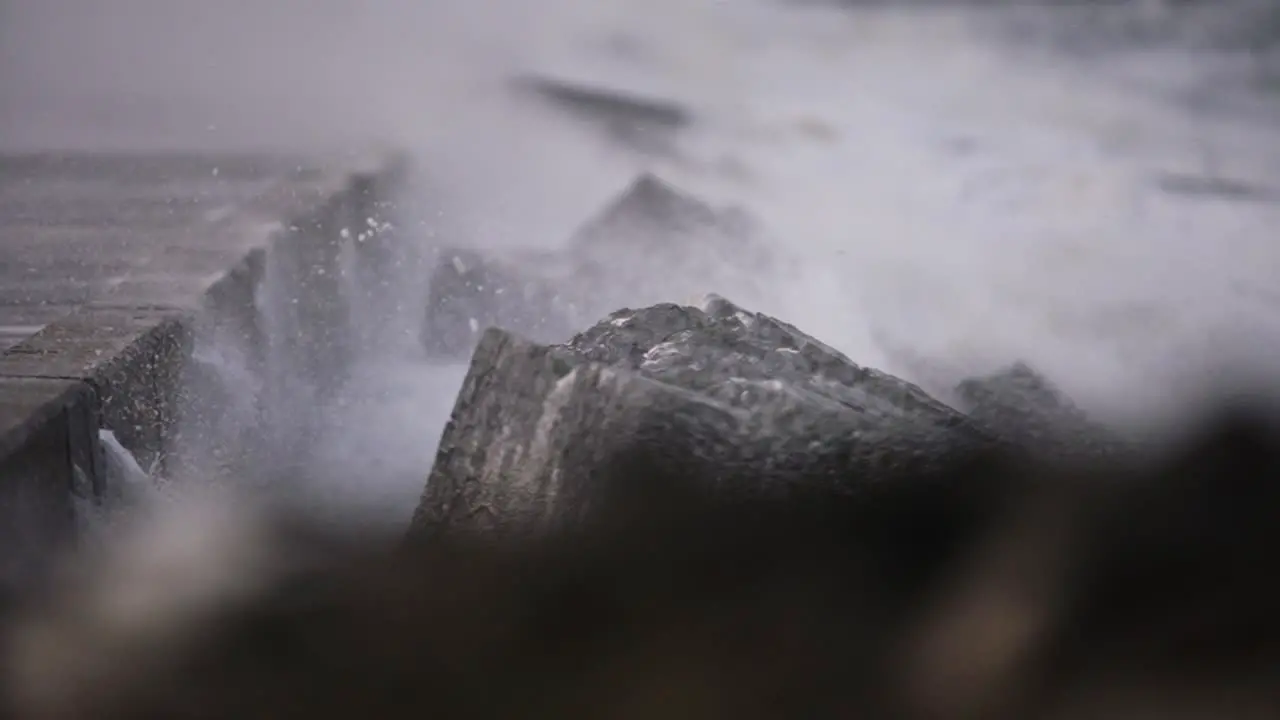 Shallow focus shot over breakwater as stormy winds blow sea spray and spume