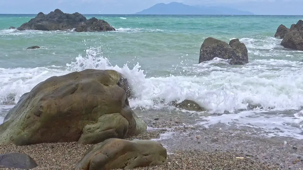 Low angle shot of waves crashing onto rocks along the coastline of Banbanon Beach Surigao Del Norte Philippines on a cloudy day