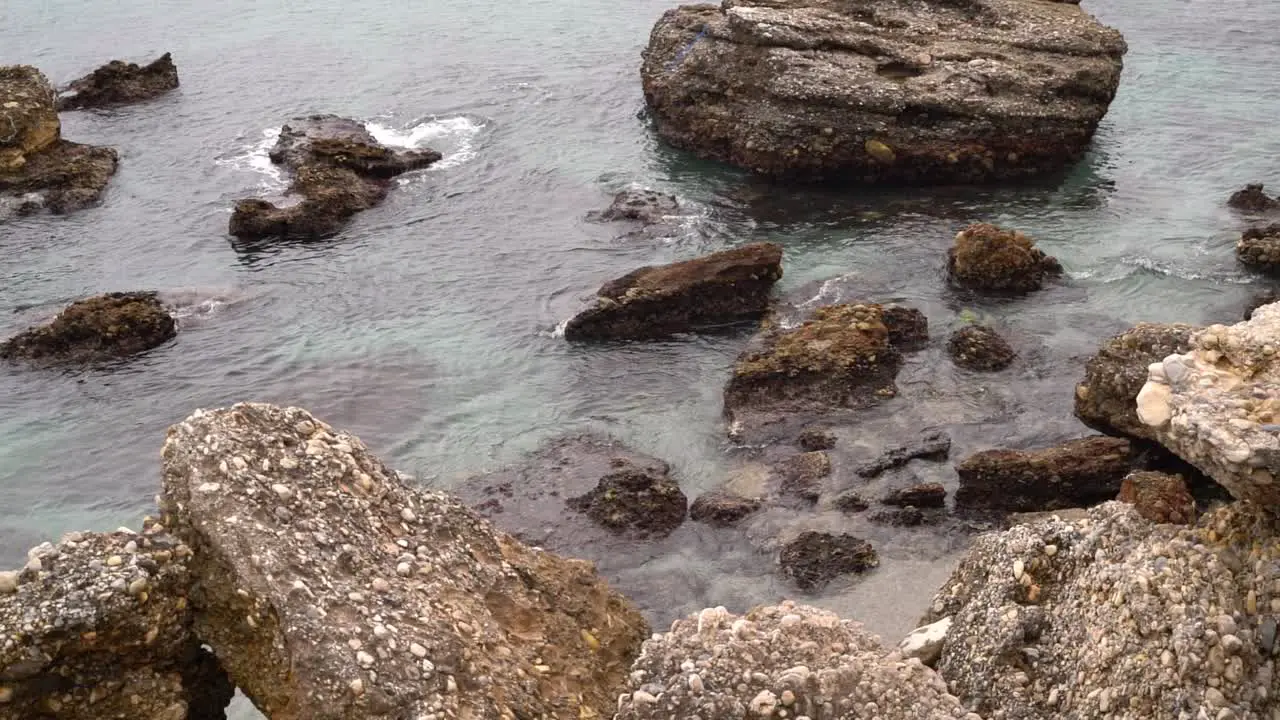 Static view over beach rocks with calm waves rolling in