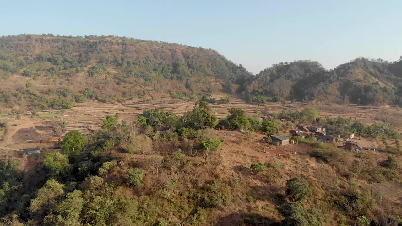 Low drone shot over a rural Indian farming village out towards their farmlands