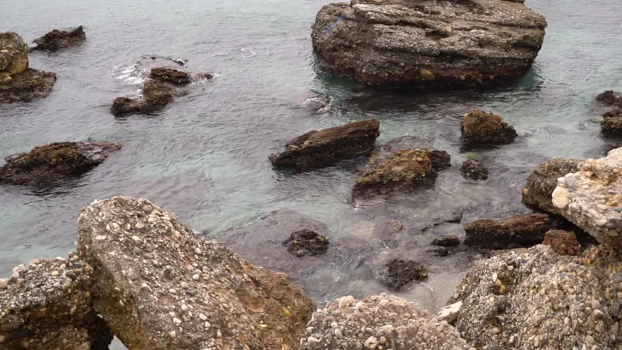 Slow motion view over shallow ocean water with rocky beach