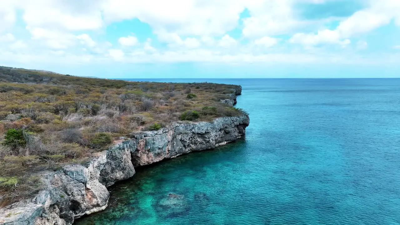 The drone is flying around cliffs above the ocean in Curacao Aerial Footage 4K