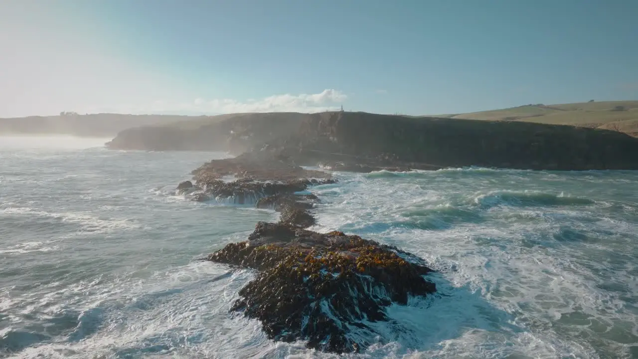 Aerial seascape view of rough wild waves breaking over kelp and seaweed covered rocks on the coastline of Slope Point in the South Island of New Zealand Aotearoa