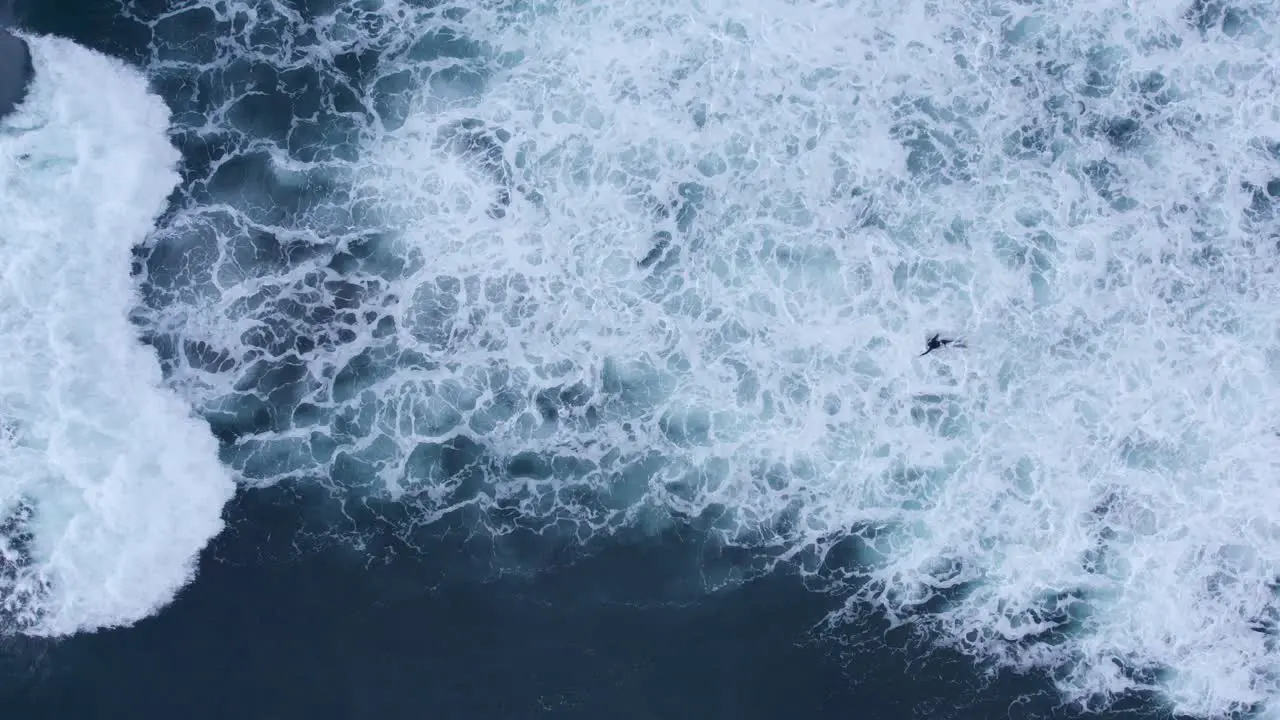 Top down aerial view of bodyboarder ducking under crashing waves rough seas