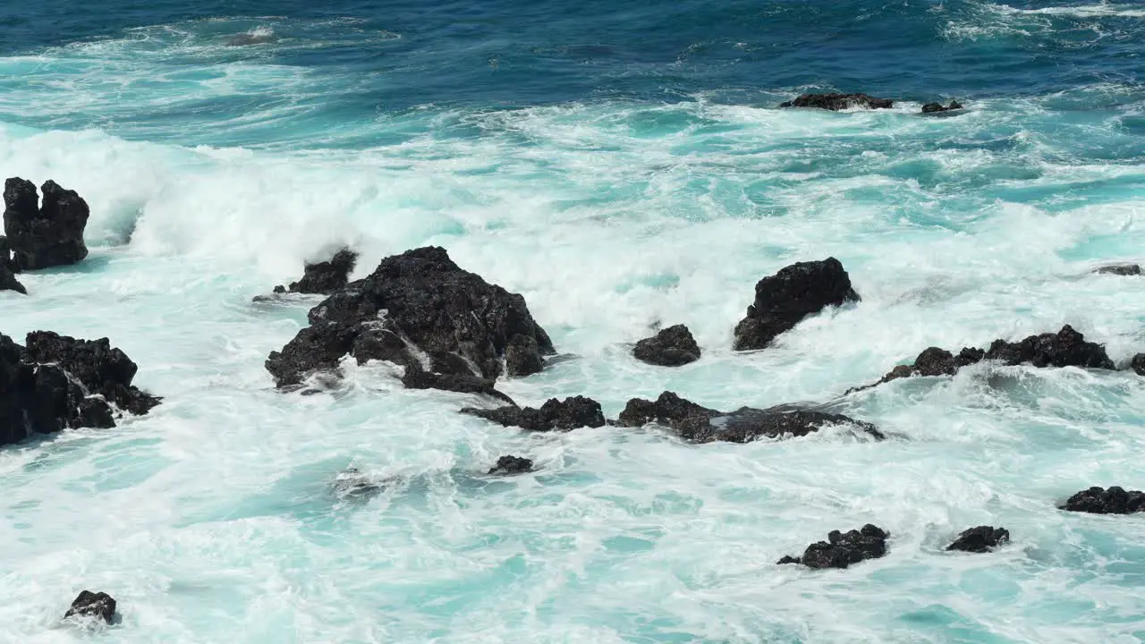 Wave creates white foam as it crashes on volcanic rocks of Tenerife