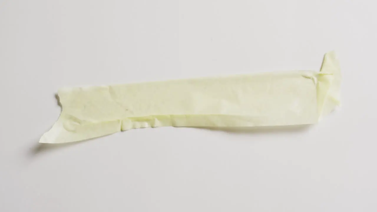 Video of close up of torn piece of yellow paper on white background