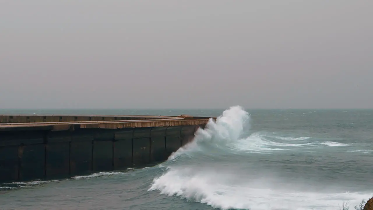 Big ocean waves crushing on breakwater and splashing