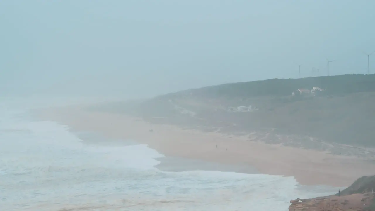 Misty ocean coast with distant wind turbines in Nazare Portugal