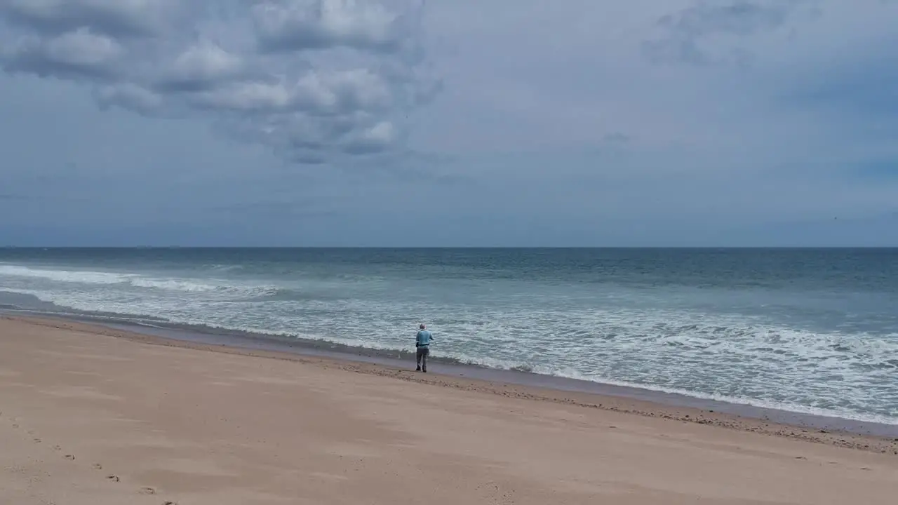 Lonely Single Fisherman Standing on Cape Cod Beach Fixing His Fishing Rod Reel