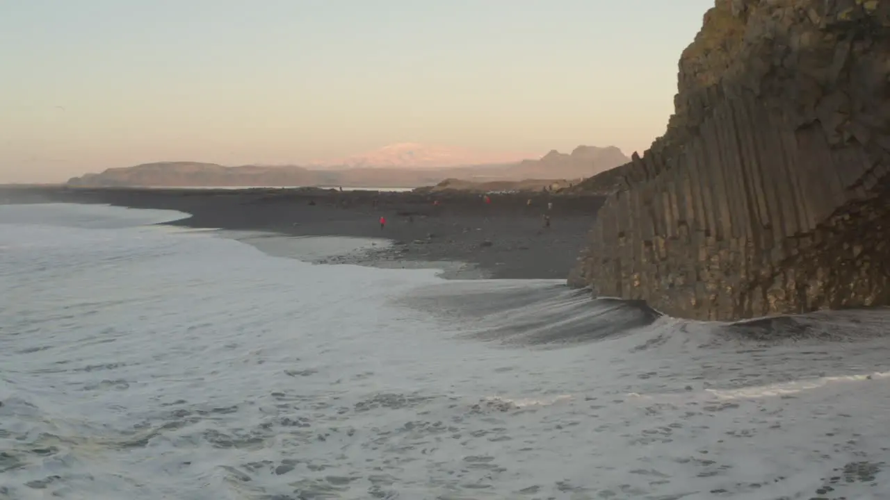 Aerial shot towards tourists on black sand beach Columnes Reynisfjara Iceland