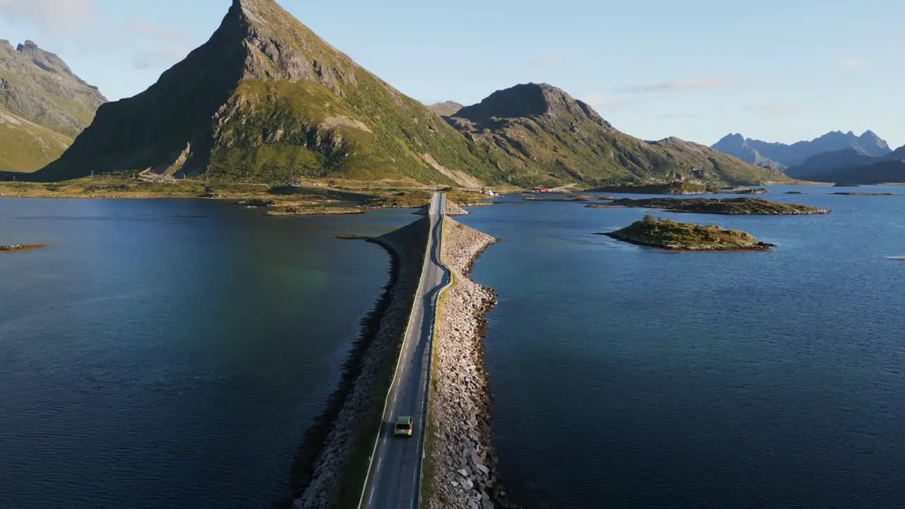 Chasing car over bridge in northern Europe with rough landscape towards the mountains