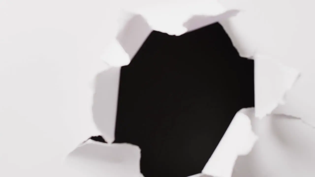 Video of close up of white paper torn on black background