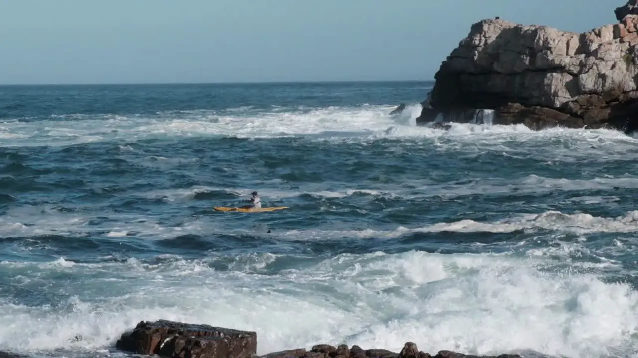 Athlete on a kayak paddling out past the surf into the ocean