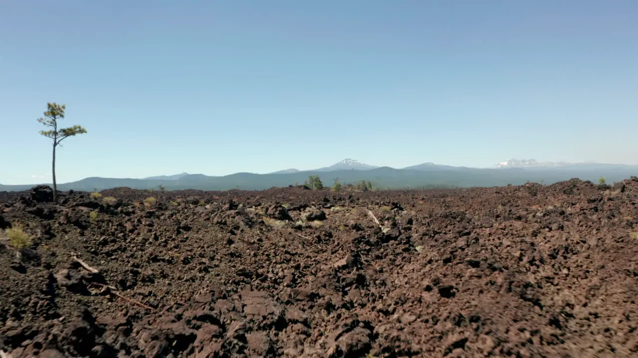 Low aerial shot over rocky lava fields towards an extinct strato volcano