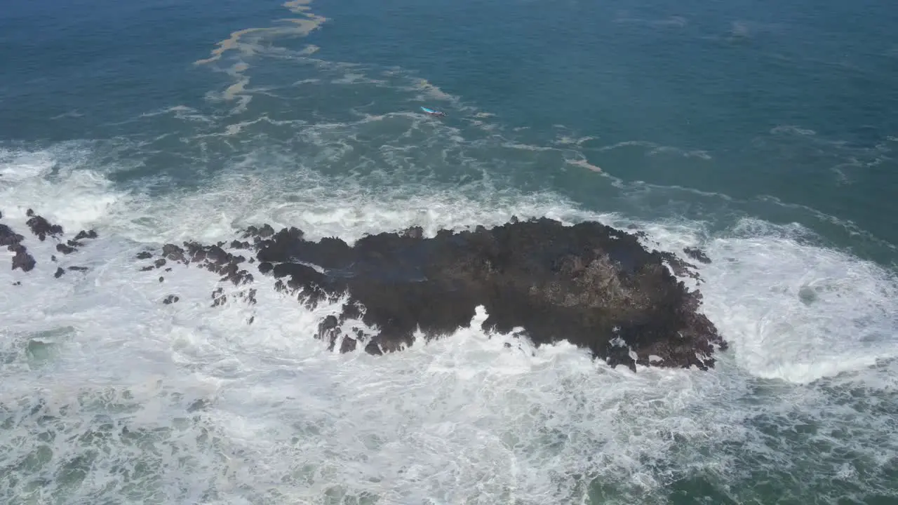 Ocean waves hitting rocky island power of sea aerial orbit view