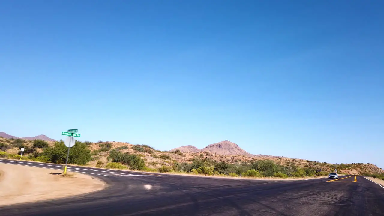 POV driving through the desert on a lonely highway past a marked lane turn off