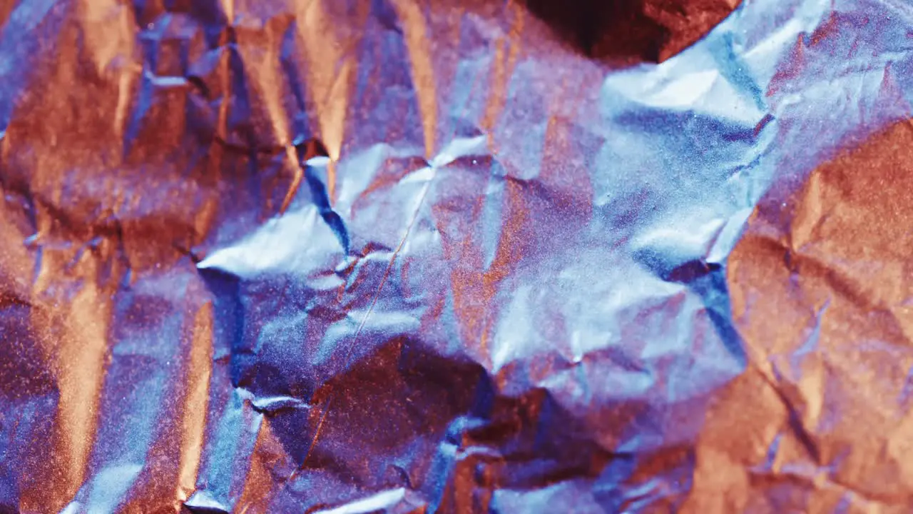 Close up of blue and brown crumpled pieces of paper in slow motion