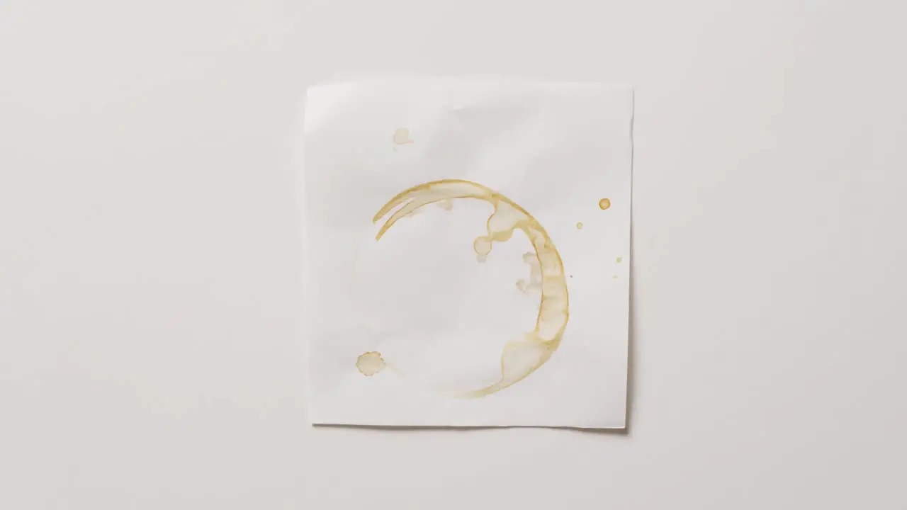 Video of close up of piece of paper with coffee mug ring stain on white background