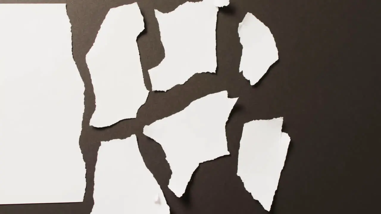 Video of close up of multiple white paper pieces on black background