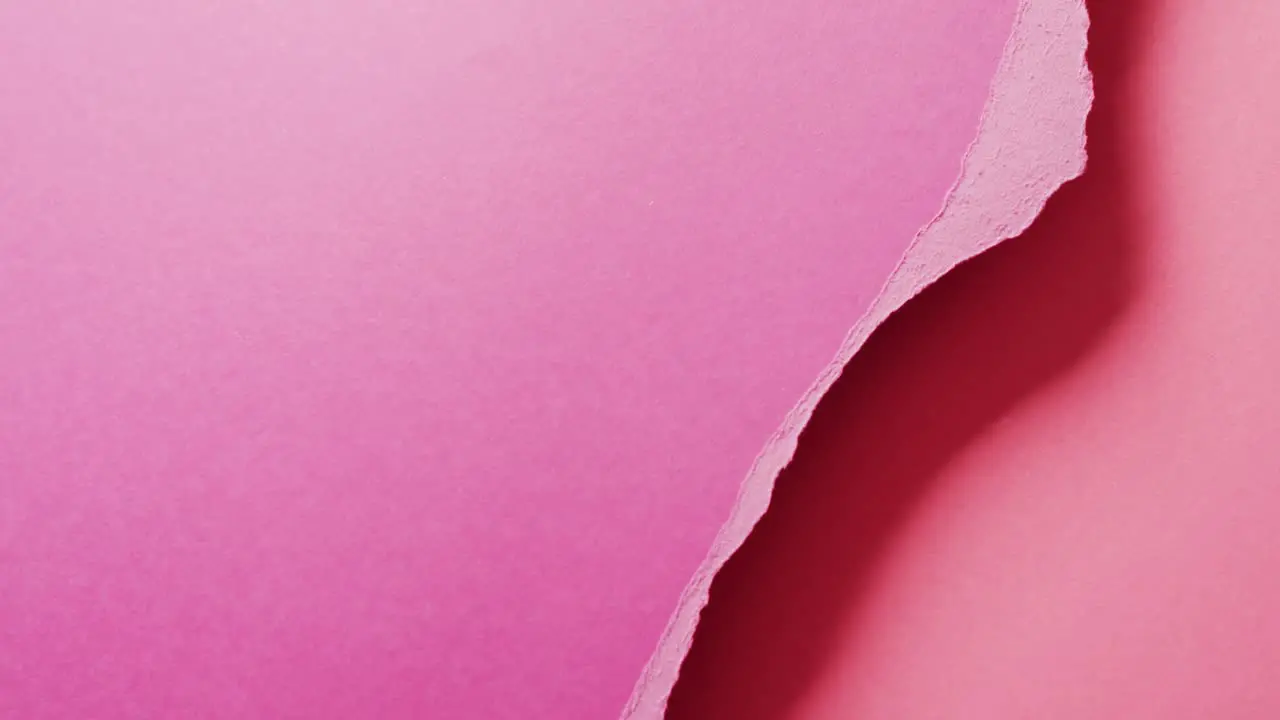 Video of close up of torn pieces of pink paper with copy space in background