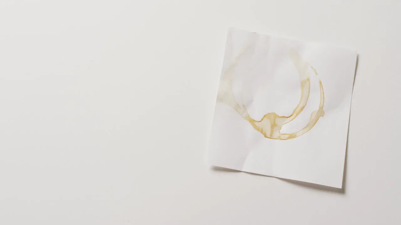 Video close up of piece of paper with coffee mug ring stains on white background