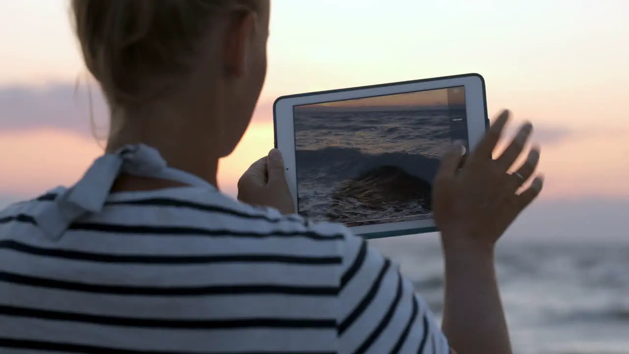 Woman making photos of sea waves with pad