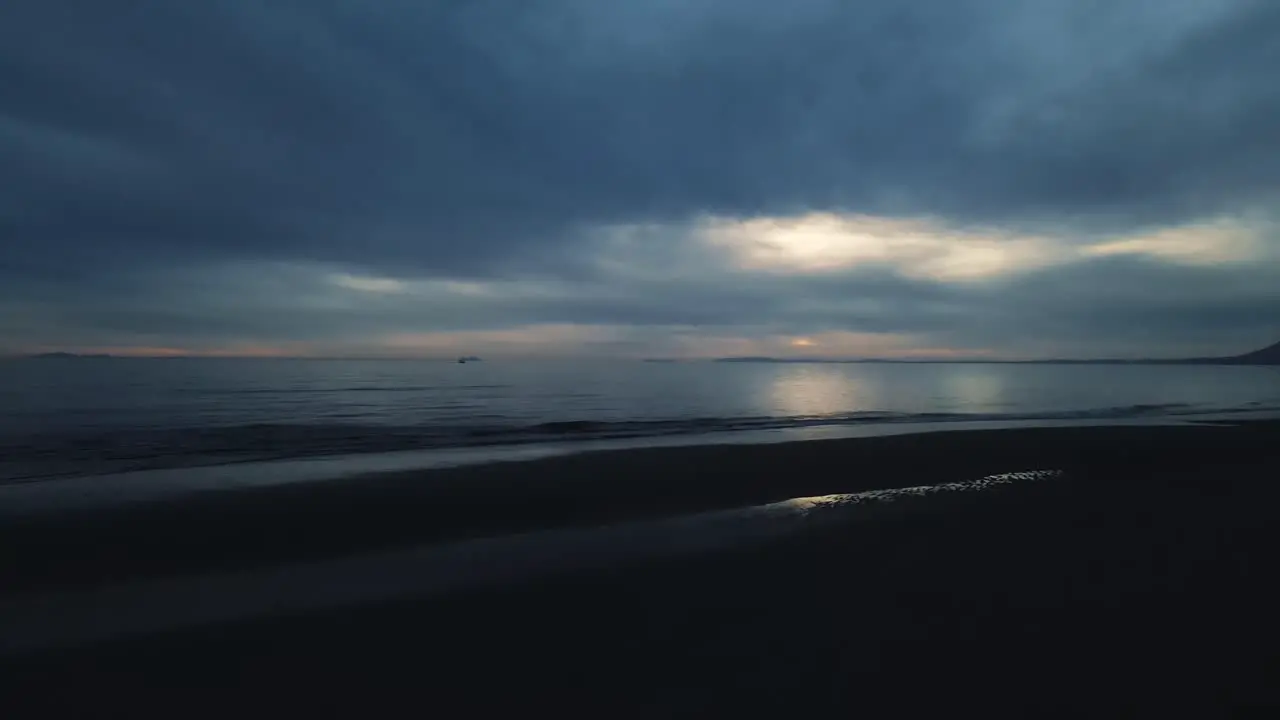 Dark view of empty beach with calm waves and dramatic sky