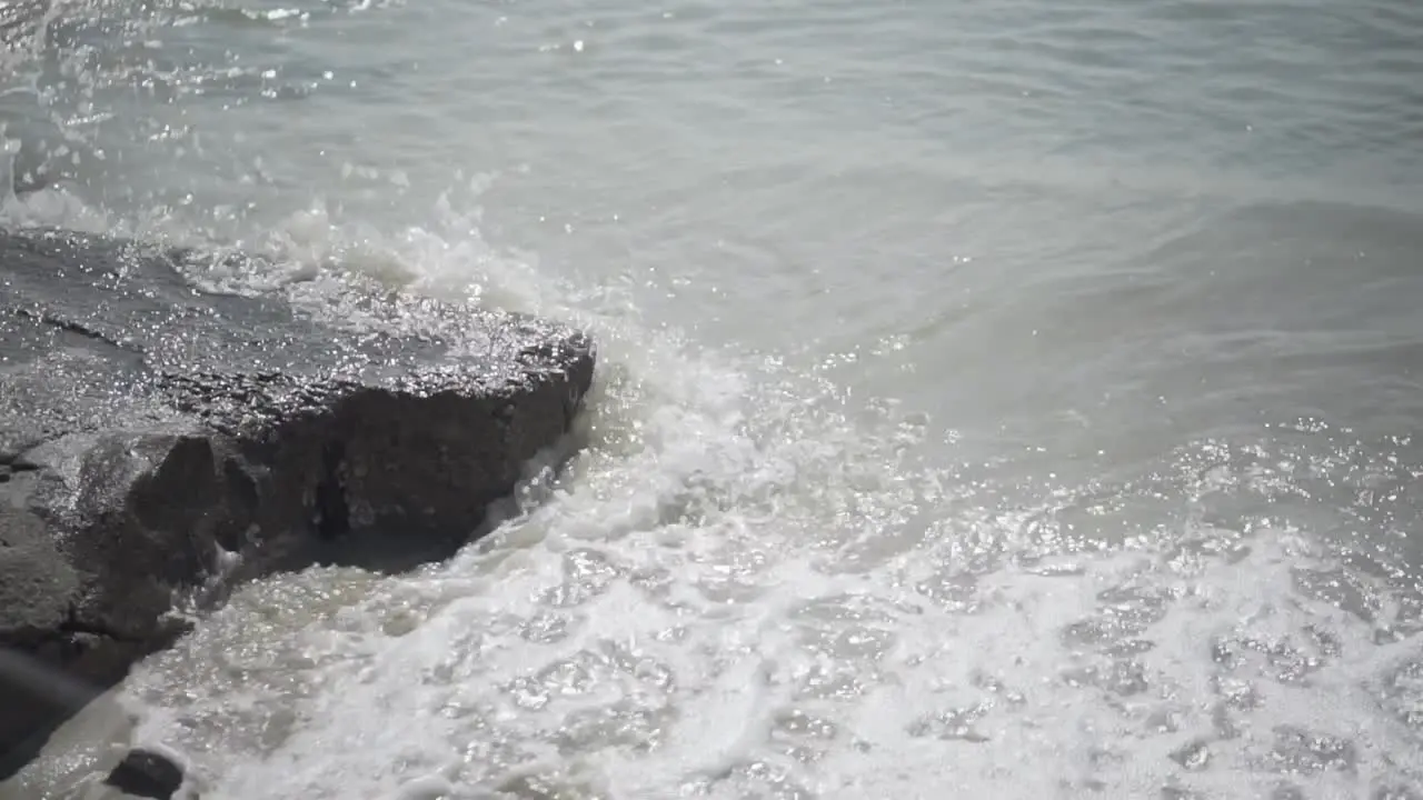 Waves crashing on rock and washing the sand