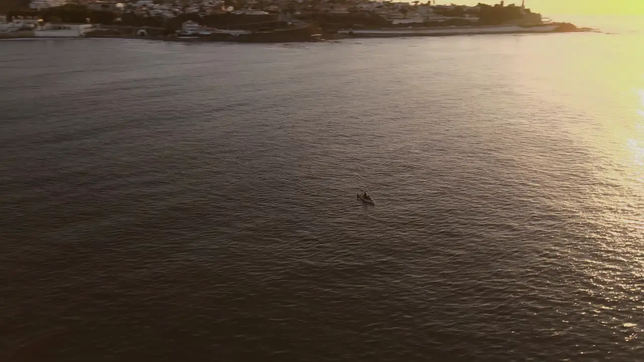 Aerial Pan Right Shot of Colorful Sunset Reflected on Sea Surface with Small Boat