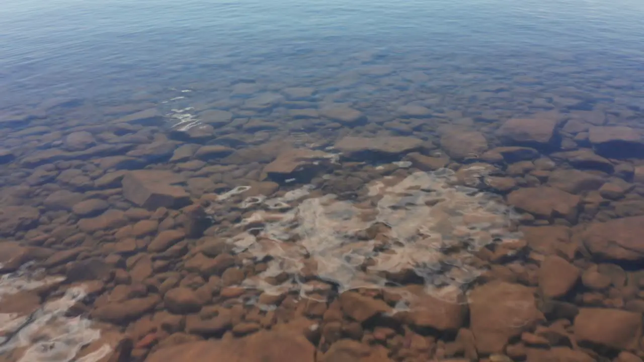 Aerial over calm clear lake water drone flying low