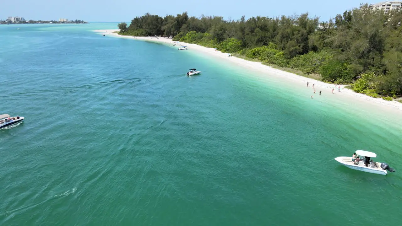 Flying over a secluded beach with boats moving and boats beached