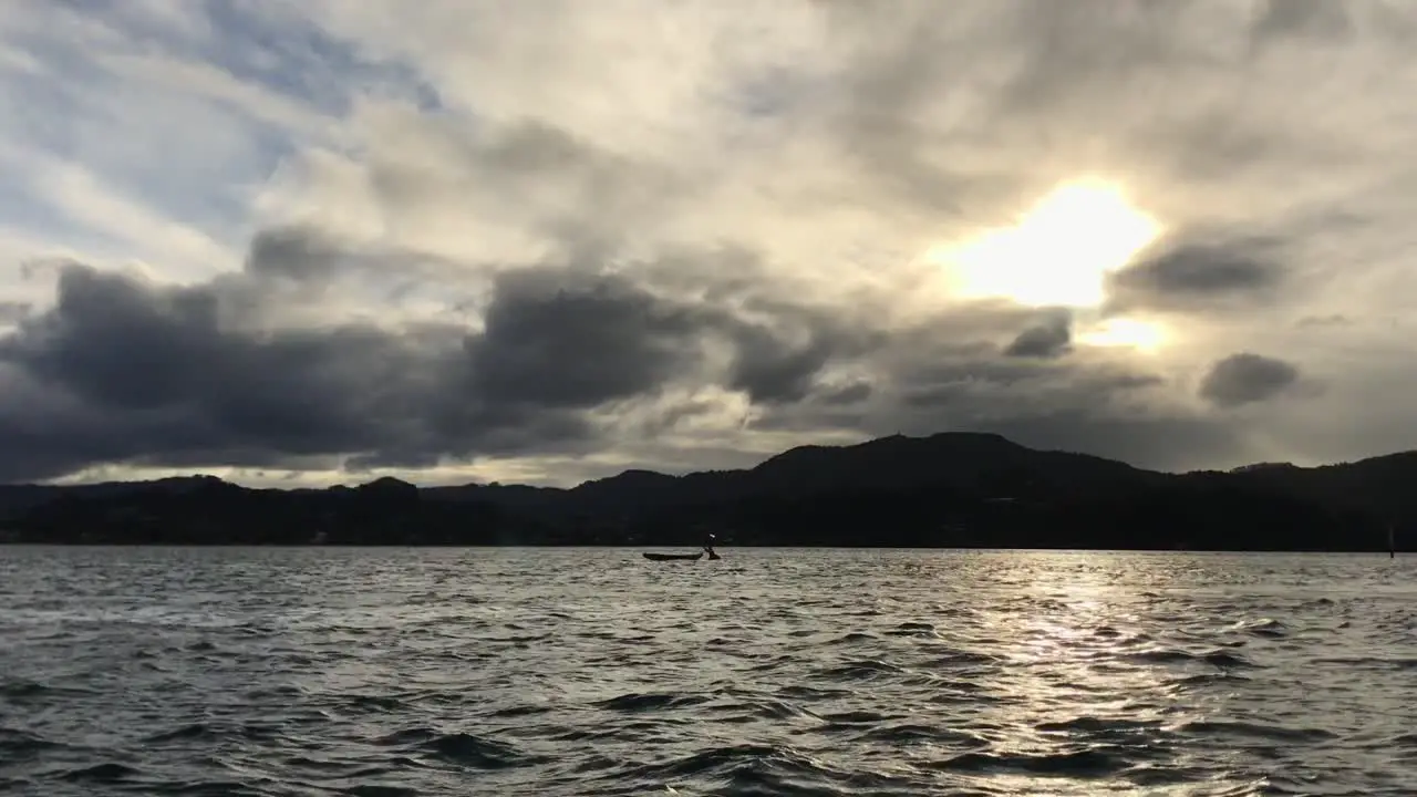 Kayak moored in the middle of an inlet floating on the rippling water during a cloudy sunset