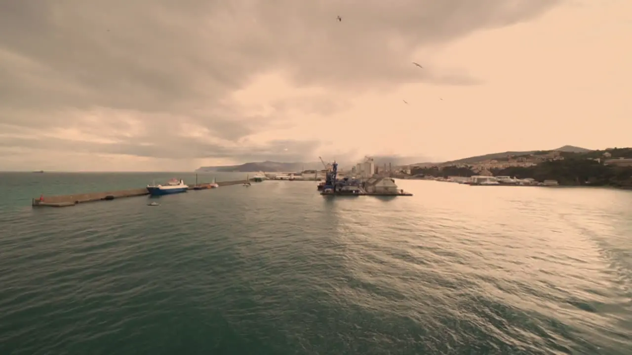 Cruise ship leaving the italian harbour of Savona at dusk with seagulls flying over the sea