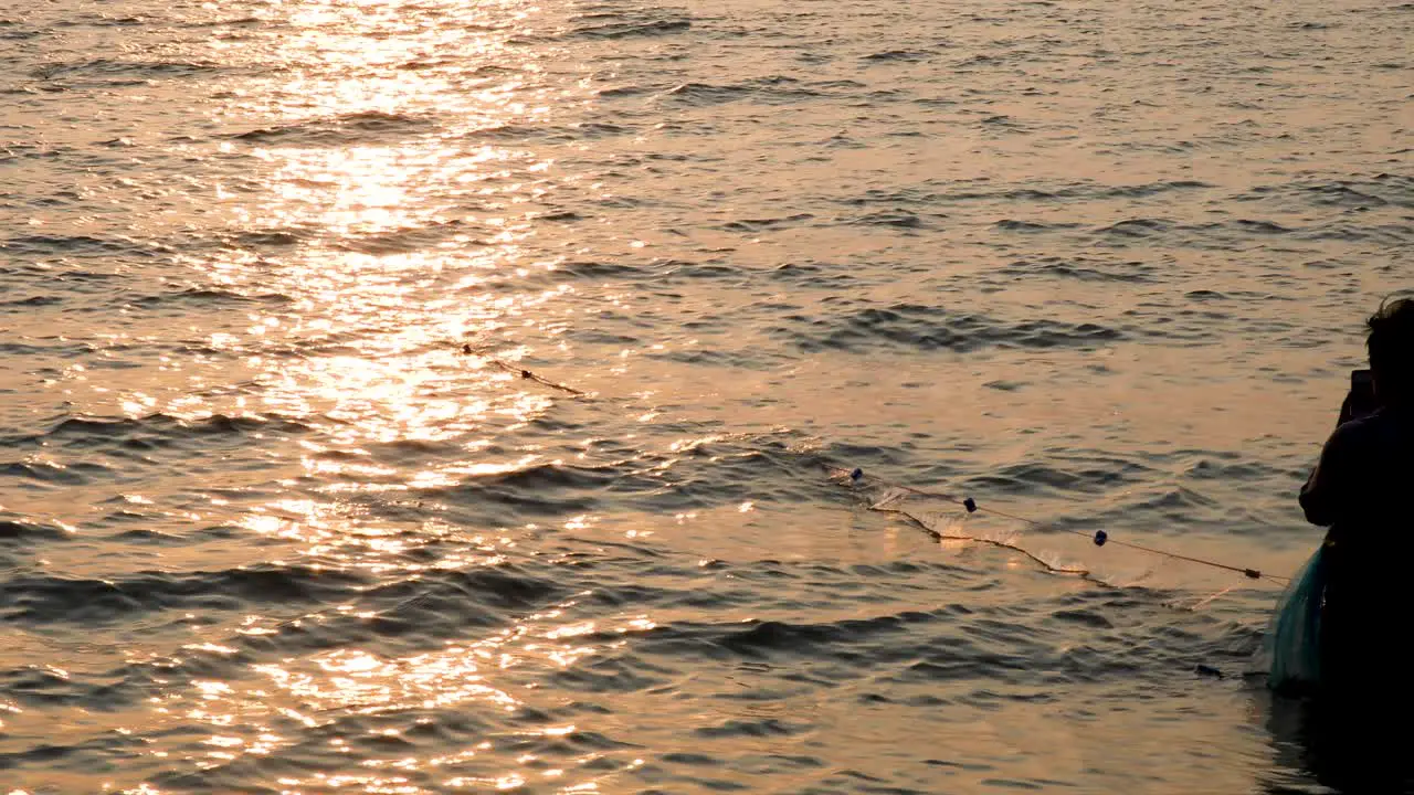 Silhouetted Woman Fishing with Reflections of a Sunset in Bangsaray near Pattaya Thailand