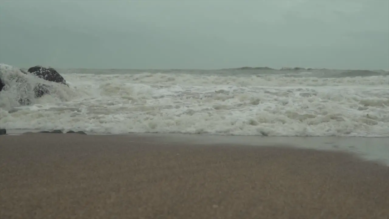 Strong waves roughly crashing on the shore on a beach with winter sky at daytime