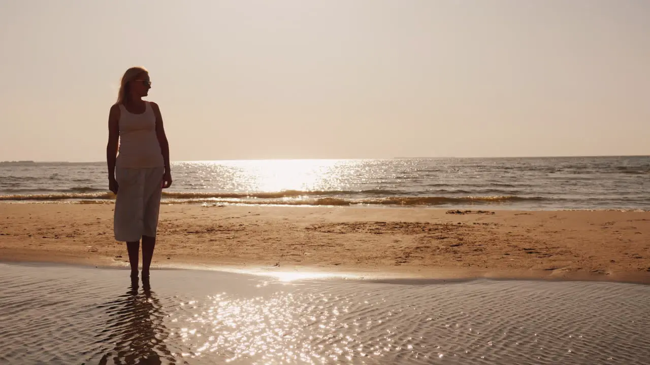 Lonely Silhouette Of A Young Man Sitting On The Sand By The Sea