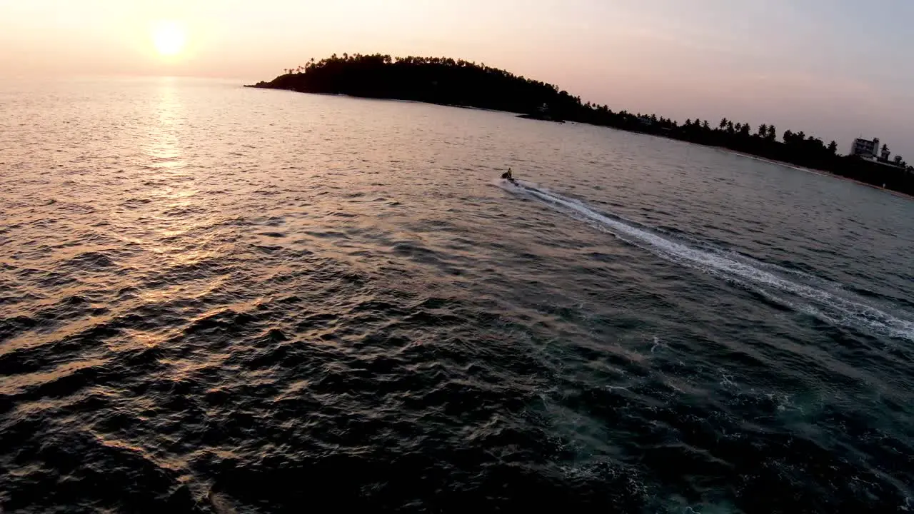 Coastal scene at sunset unrecognizable people riding jet ski