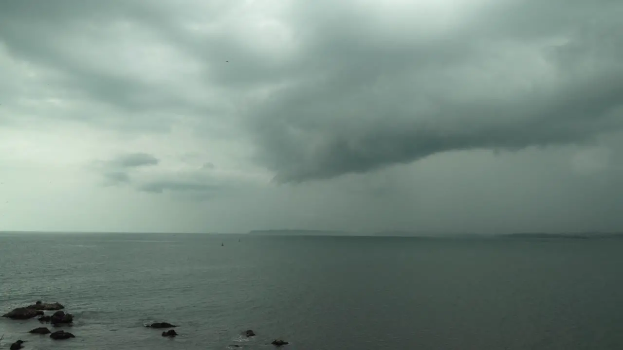 Static time lapse shot of a large lake with calm water and rocks in the water during a cloudy day