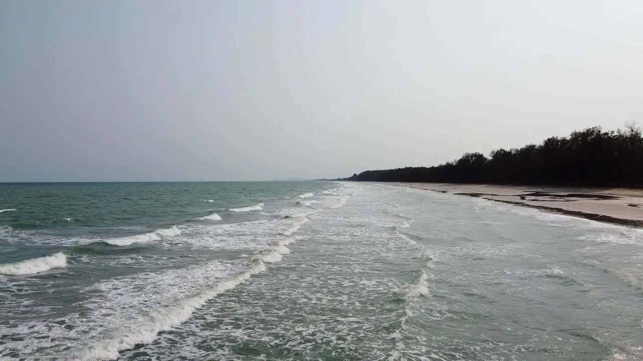 Aerial side view of Long Ocean waves reach the shore in Southern Thailand