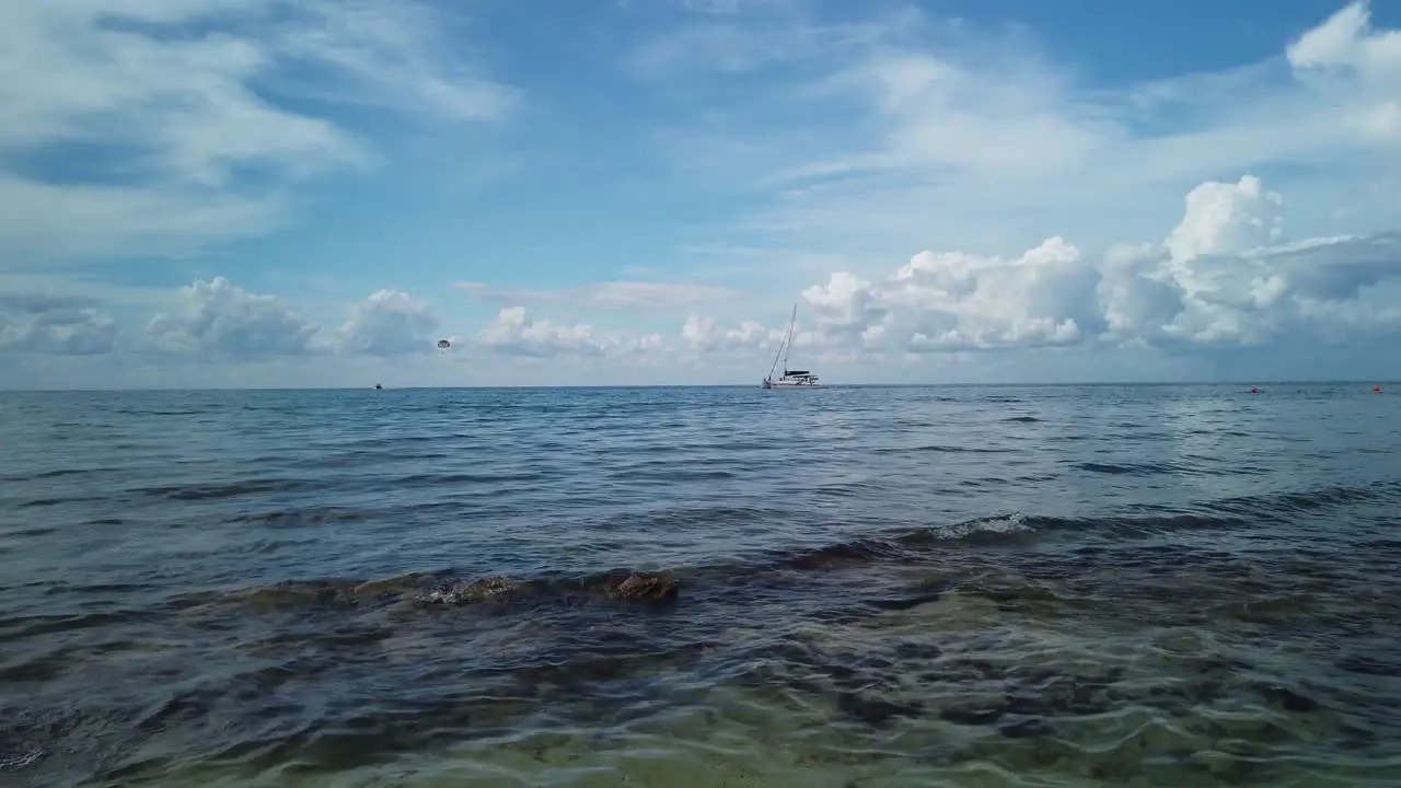 Low angle view of clear warm turquoise ocean with a catamaran on the horizon