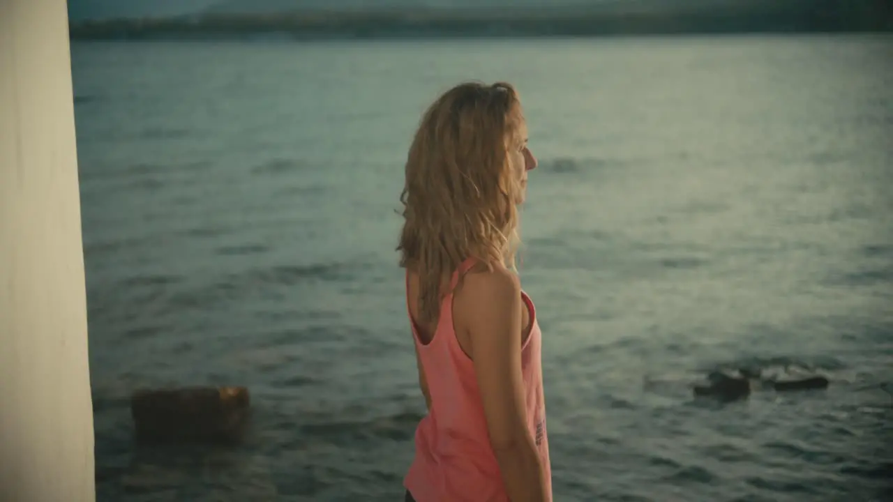 Happy blonde woman standing in front of sea and attending around