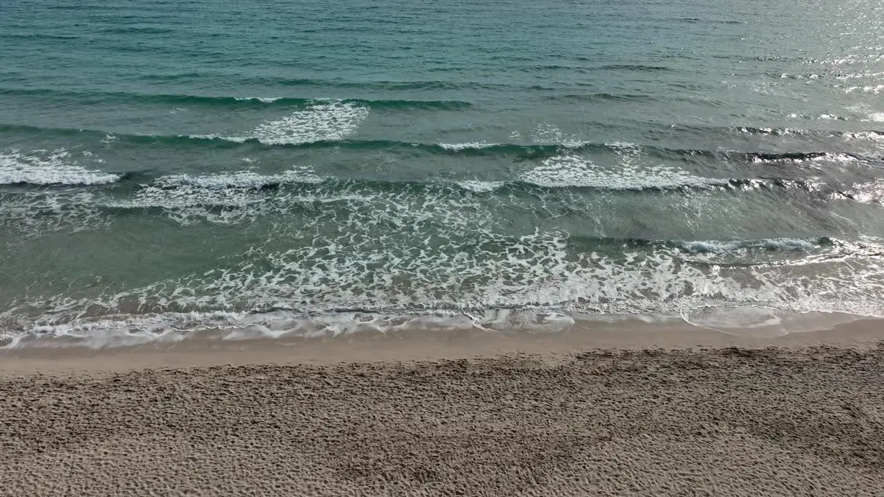 Fly right and panning up over beach with waves