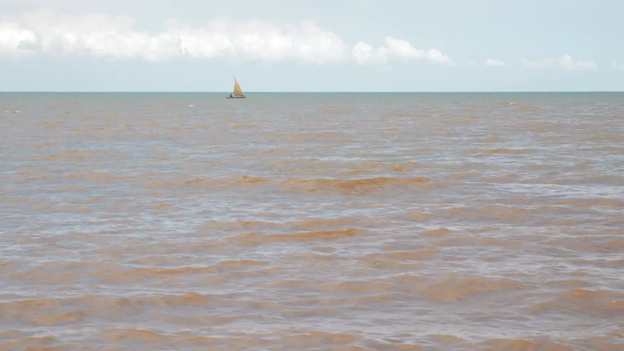 Lonely african fisherman in his small boat sailing in muddy ocean from nearby river